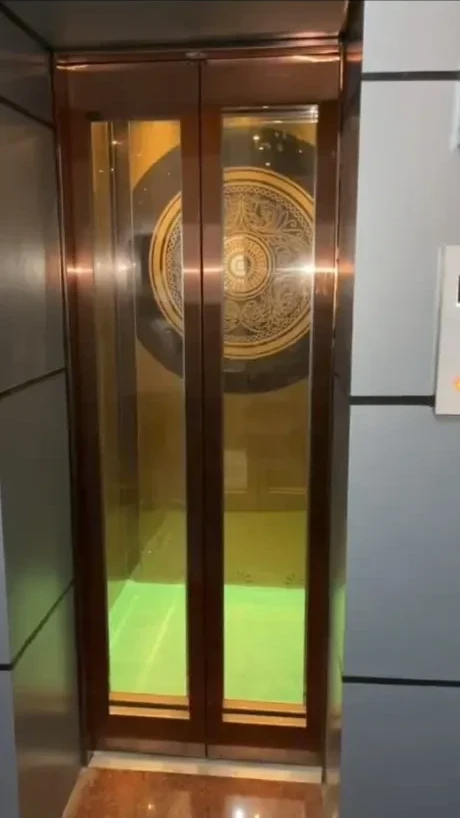 Newly installed gold stainless glass passenger lift with automatic doors